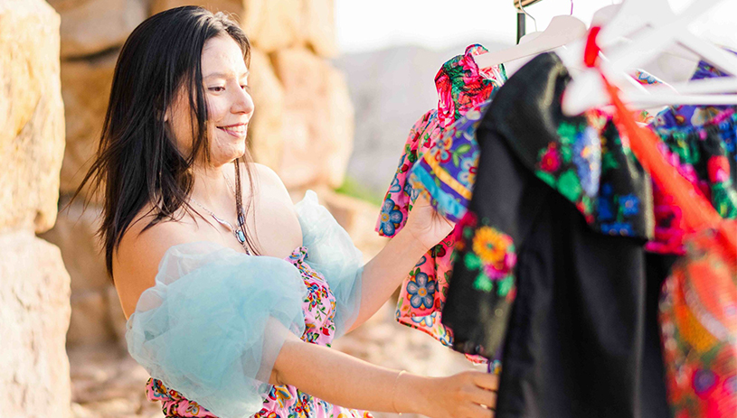 Masani's Beauty - woman looks through rack of custom-made clothes. Photo Courtesy of Change Labs