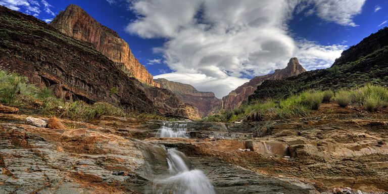 Stone Creek waterfall in Grand Canyon National Park, small waterfall flowing along rocky bed with cliffs looming above