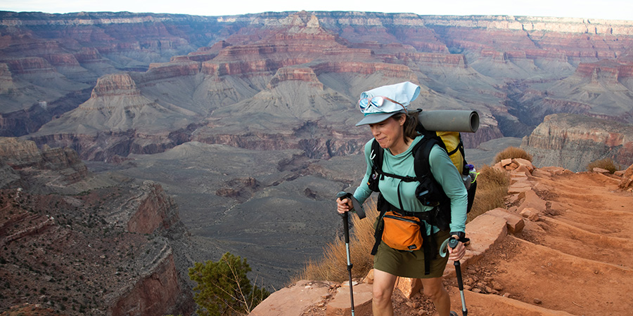 Woman with trekking poles hiking up the trail with a large backpack in the Grand Canyon