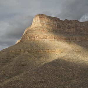 Light shines through cloudy skies, highlighting the cliffs above Clear Creek