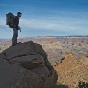 A hiker stands on a rock overlooking the Grand Canyon from the South Kaibab Trail