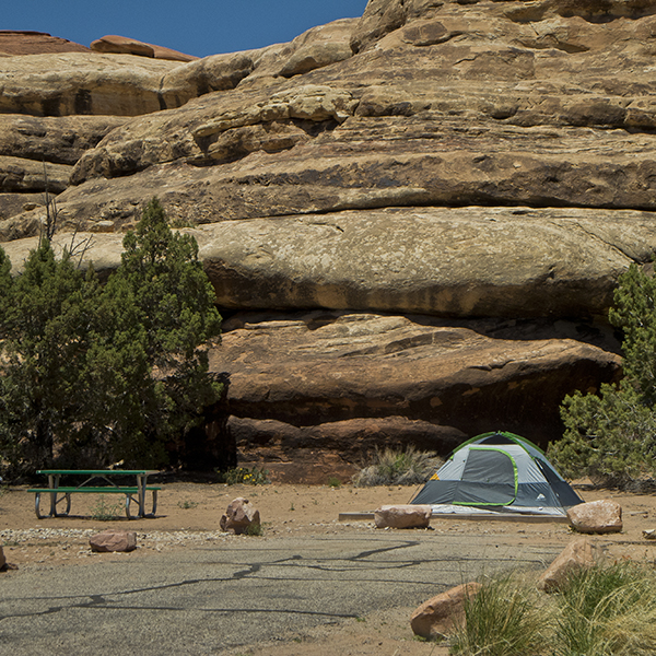 A tent and picnic table next to sandstone ledges