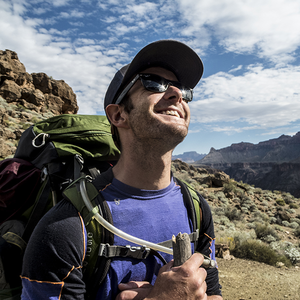 The sun reflects off the sunglasses of a smiling male hiker in the Grand Canyon