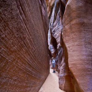 A hiker a tight sandstone slot canyon