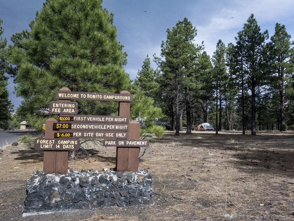 The campground entrance with a brown sign that lists the prices