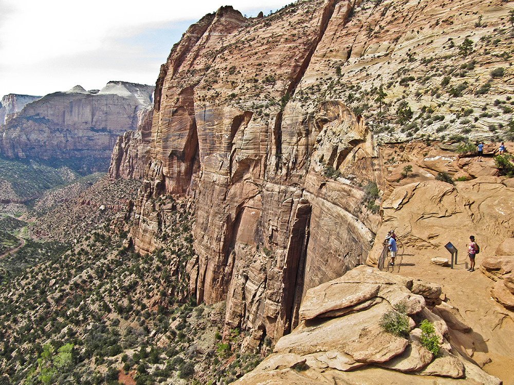 A hiker on a slickrock saddle overlooking Zion Canyon