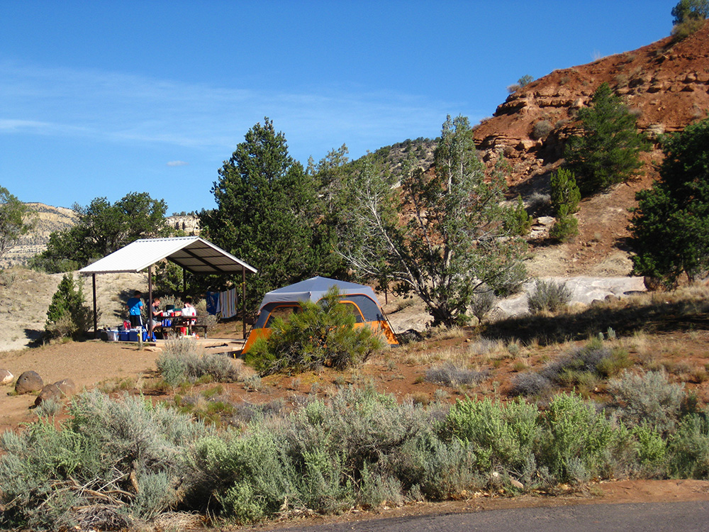 A campsite set up against red cliffs