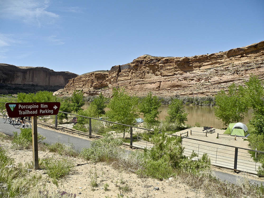 Grandstaff Campground from the road, with a brown BLM sign pointing to trailhead parking