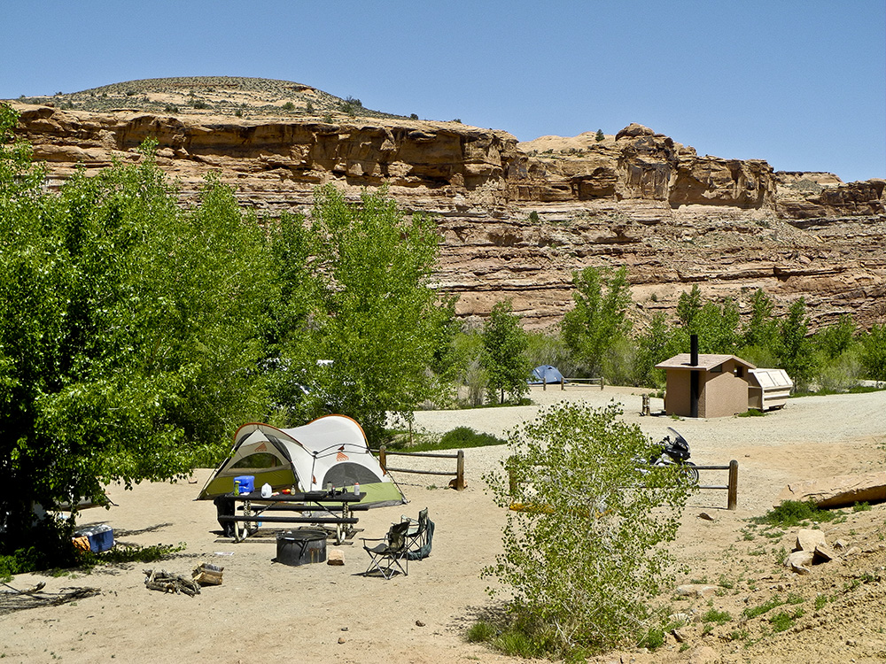 A green and tan tent, fire ring, and camp chair set up at a campsite in Grandstaff Campground