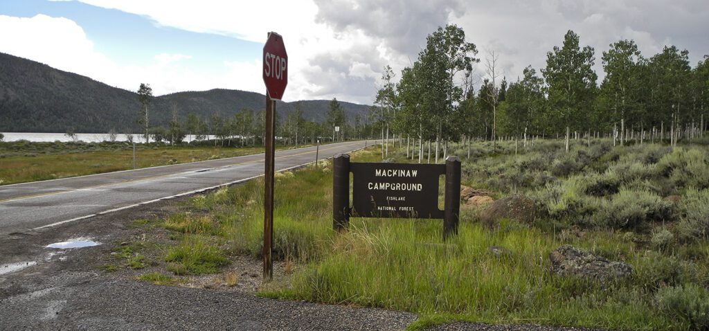 A brown sign with the name Mackinaw Campground near a stop sign at the entrance to the campground