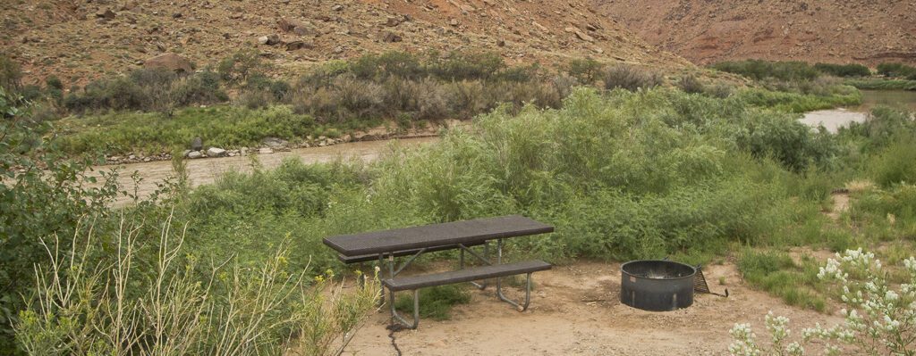 a campsite with a picnic table and fire ring along the banks of the Colorado River