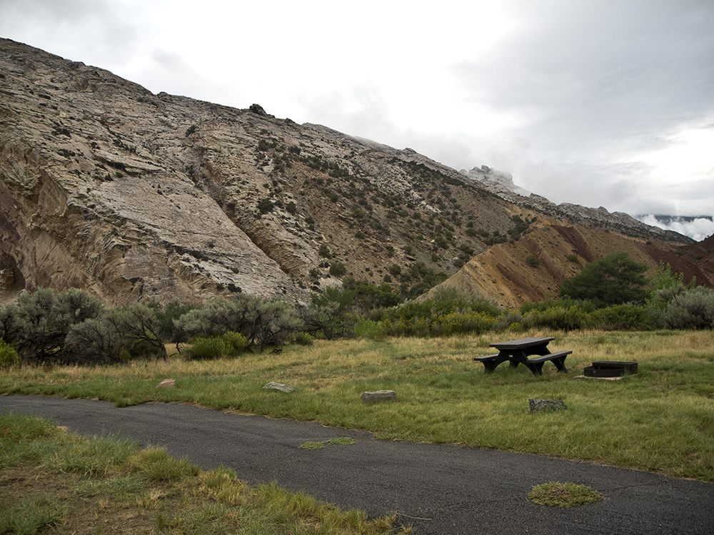 A rising slope of sandstone butting up against a campsite at the Split Mountain Campground