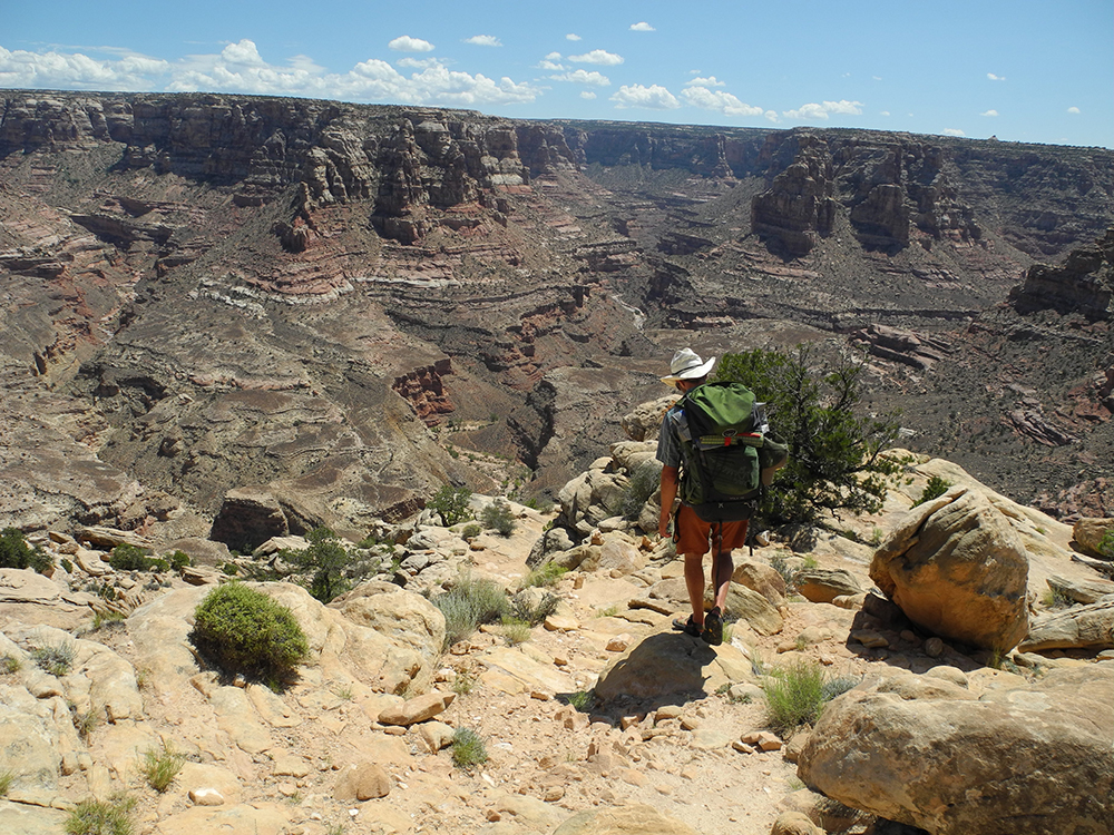 A hiker starts the rocky descent into the tributary canyon