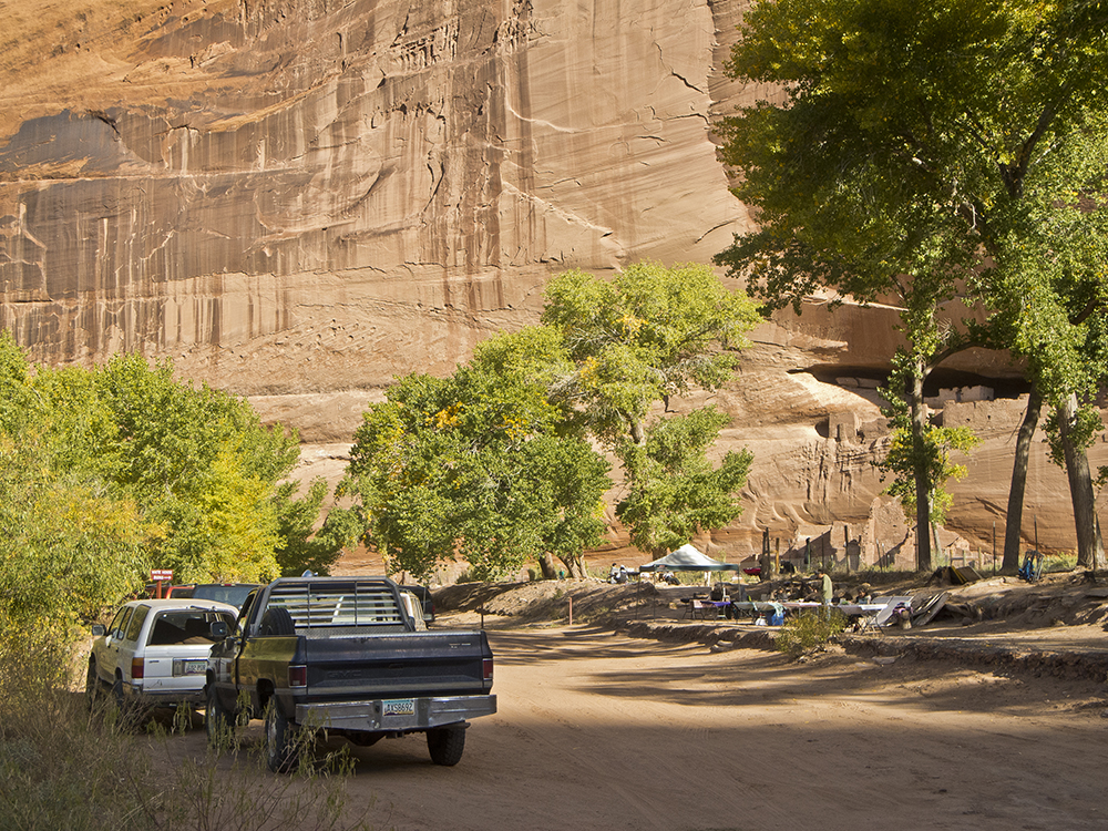 A view of the canyon floor with two cars and a camp