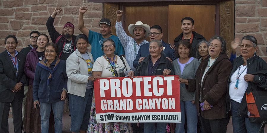 Save the Confluence members stand outside the Navajo Nation Council building holding a sign that says Protect Grand Canyon Stop Grand Canyon Escalade after the final vote striking down the proposal