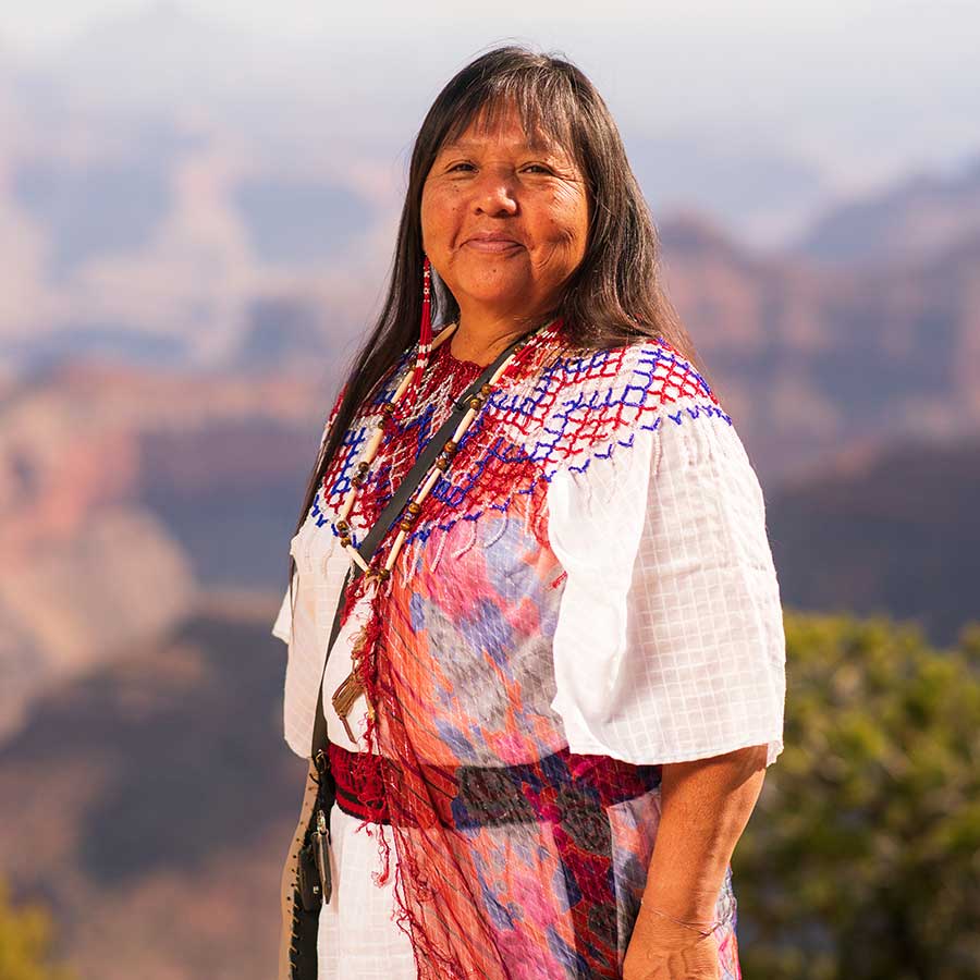 Colleen Kaska, Havasupai woman in white with traditional garments and long black hair standing at the rim of the grand canyon