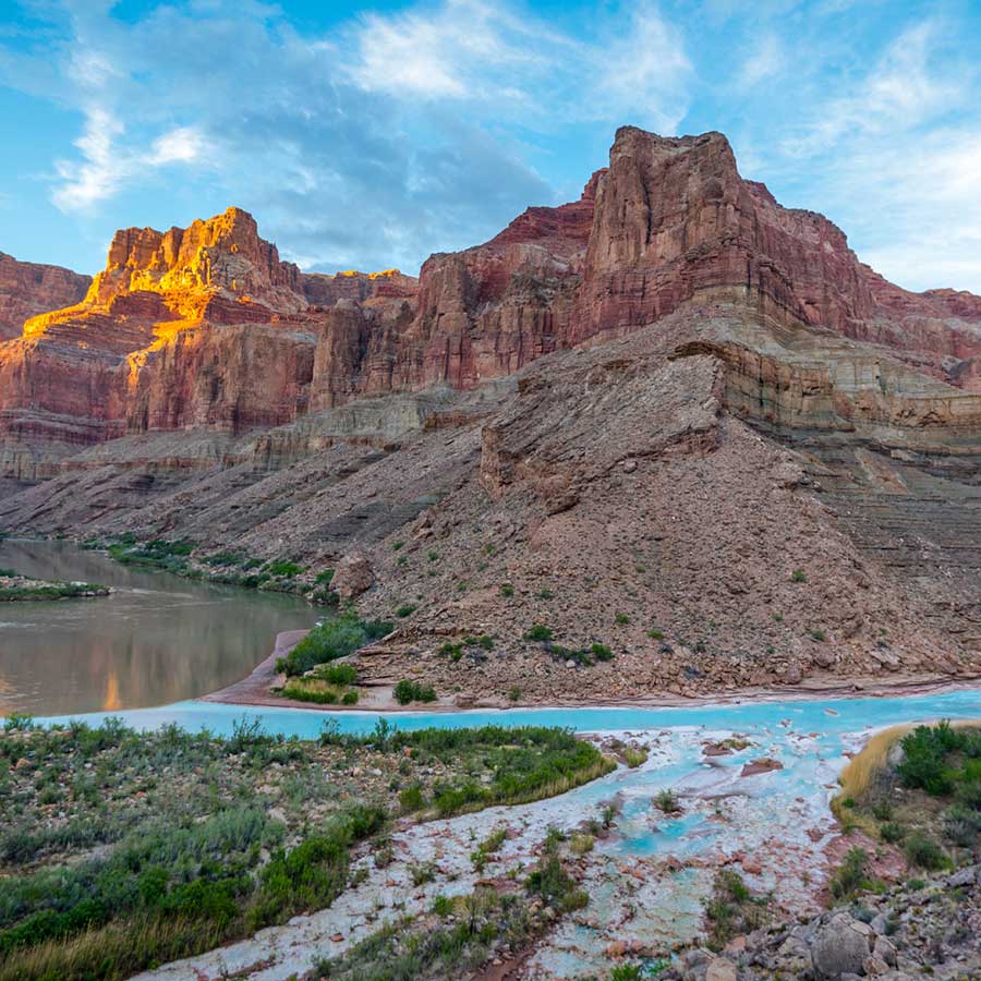 The bright turquoise waters of the Little Colorado River meet the green Colorado River with grand canyon cliffs all around