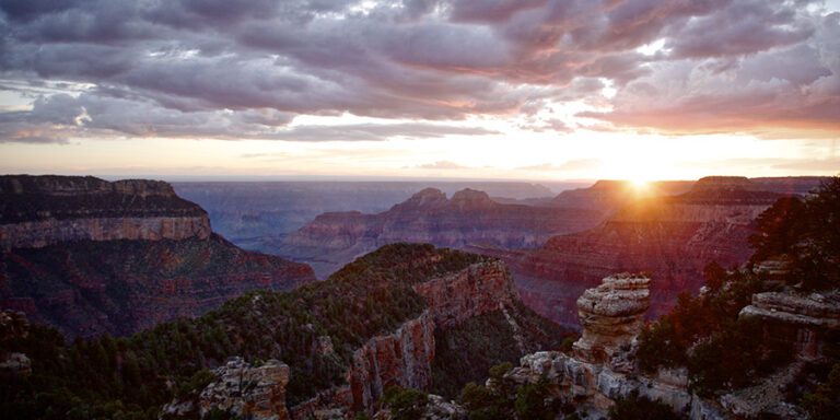 Sunstar at the edge of the Grand Canyon with dramatic clouds