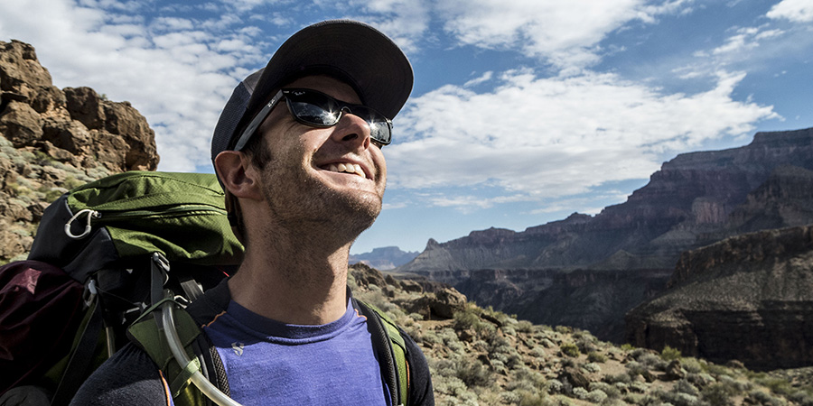 Grand Canyon backpacker pausing hiking to gaze up with sun stars shining off his sunglasses on the Tonto Trail near Hermit Rapid in Grand Canyon National Park.