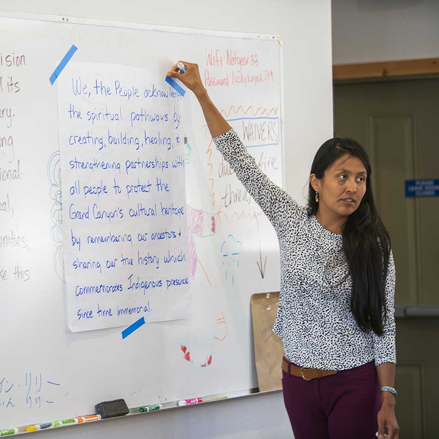 Colleen Cooley takes notes on a white board while facilitating an intertribal centennial conversations group meeting