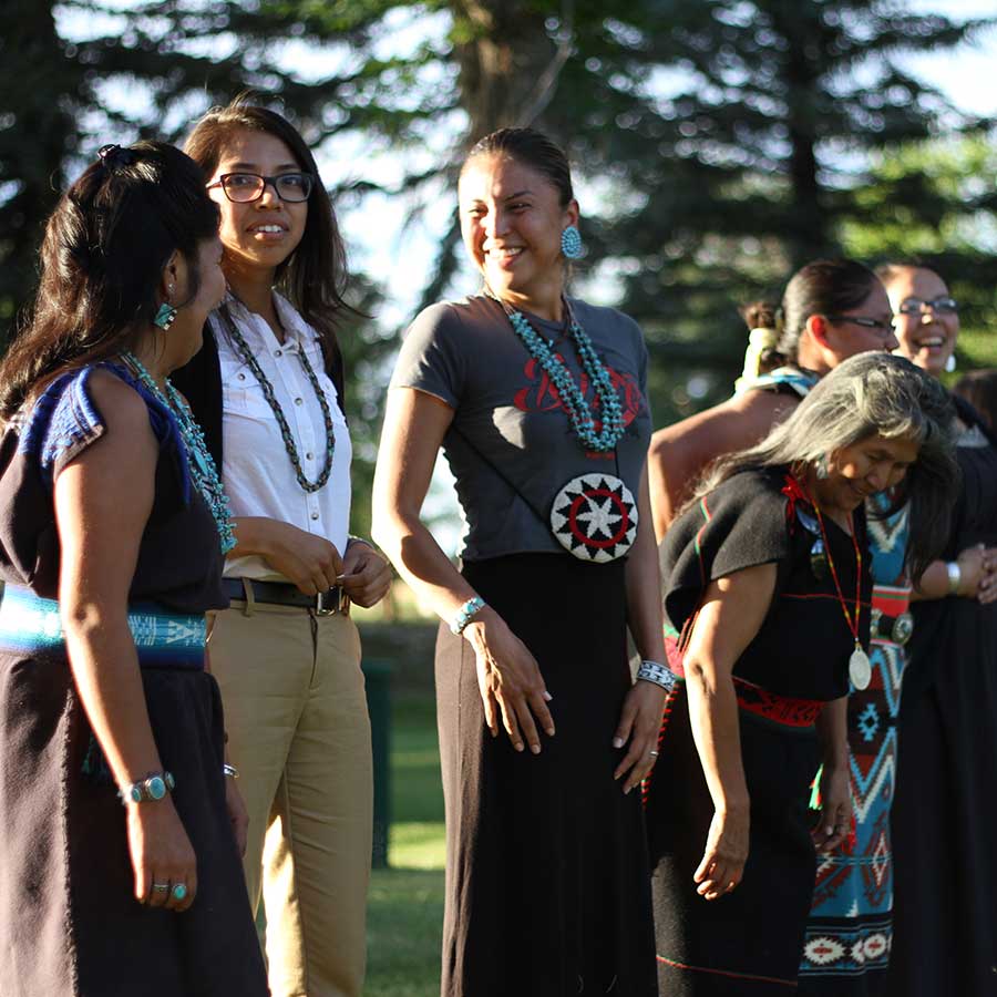 Intertribal youth smile and converse on a lawn outside an intertribal gathering