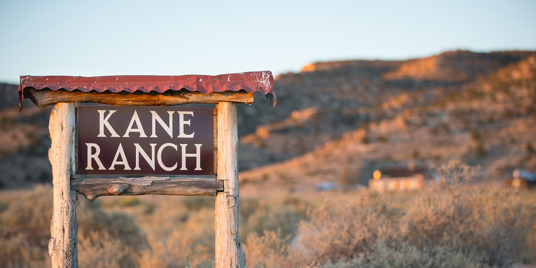 Kane ranch sign with scrub-covered hills in the background on the North Rim Ranches