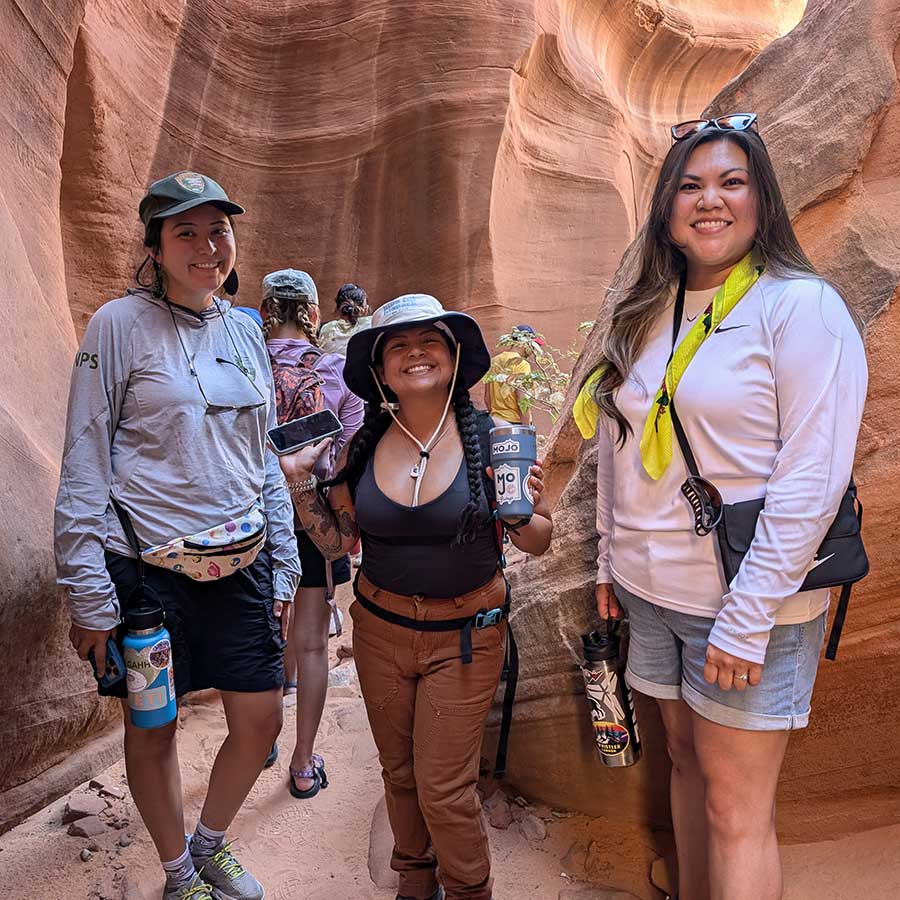 Three young Native women in a slot canyon during a rising leaders outing