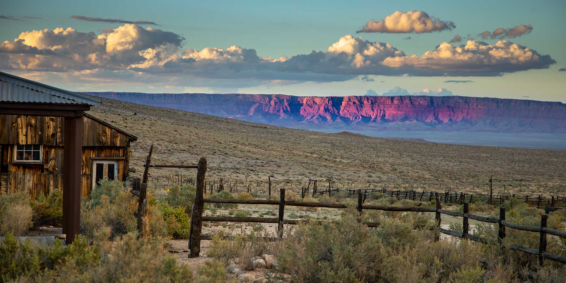 A rustic historic ranch house on the North Rim Ranches with the Vermilion Cliffs in the background.